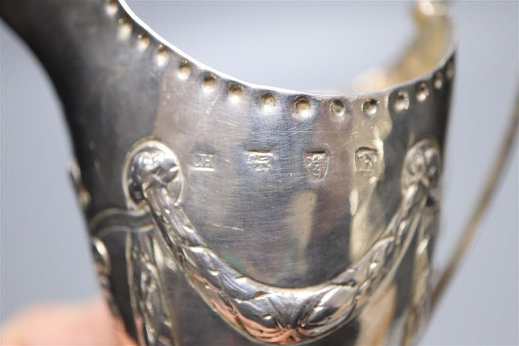 A George III silver helmet shaped cream jug, with later embossed decoration, London, 1773, 14cm, 88 grams (a.f.).